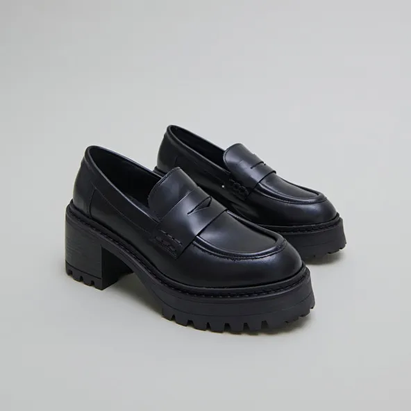 Heeled loafers with notched soles in black shiny leather