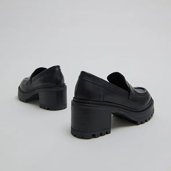 Heeled loafers with notched soles in black shiny leather